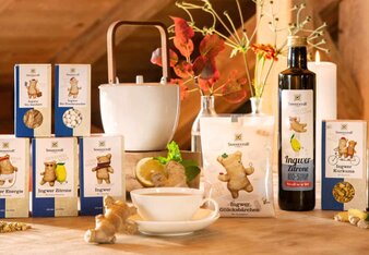 The photo shows the entire Sonnentor ginger product range. The products are on a table together with candles and flowers. | © SONNENTOR