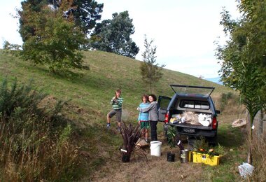 Photo of a woman and two children next to a car during tree reforestation. | © SONNENTOR