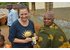 In the photo there are several people in a village. Two women are holding a pack of cloves.