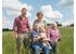 Photo of family Zach standing and sitting with dog in a field.