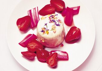 Auf dem Foto ist Flower Power Panna Cotta zu sehen. Daneben sind Erdbeer und Rhabarber Stückchen zu sehen. | © SONNENTOR