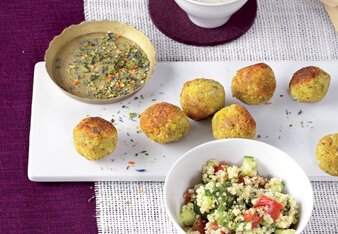 Auf dem Foto ist ein weißes Tablett mit Falafeln darauf zu sehen. Daneben steht eine Schüssel mit Tabouleh und ein Schüsselchen mit Dip. | © SONNENTOR