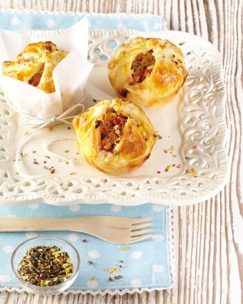 Auf dem Foto sind drei gefüllte Glücks Muffins zu sehen. Davor liegt eine Holzgabel und ein kleines Schüsselchen mit Glücksgewürz. | © SONNENTOR