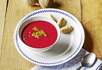 Auf dem Foto ist Rote-Rüben-Cremesuppe zu sehen. Daneben liegen Dinkelgrieß Nockerl auf dem Unterteller.  | © SONNENTOR