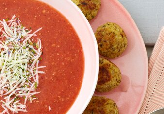 Auf dem Foto sieht man eine Tomaten-Basilikum-Suppe mit Parmesan. Auf dem Unterteller sieht man Hirse-Parmesanbällchen. | © SONNENTOR