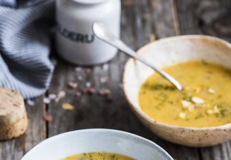 Auf dem Foto sind zwei Teller mit gelber Gemüsesuppe zu sehen. Die Suppen sind mit vielerlei Kräuter mariniert. | © SONNENTOR