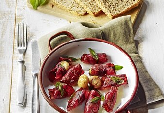 Auf dem Foto ist eine Pfanne mit Maroni-Saltimbocca zu sehen. Daneben sieht man auf einem Holzbrett drei Scheiben Brot. | © SONNENTOR