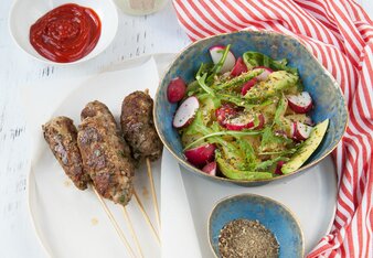 Auf dem Foto sind Spieße mit Cevapcici zu sehen. Daneben sieht man eine Schüssel mit Salat.  | © SONNENTOR