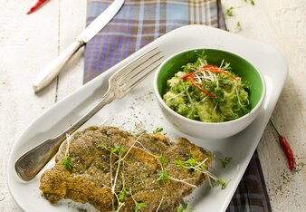 Auf dem Foto sieht man ein Zanderfilet mit Parmesankruste. Daneben steht ein Schälchen mit Dip. Über den ganzen Teller sind Knospen verteilt. | © SONNENTOR