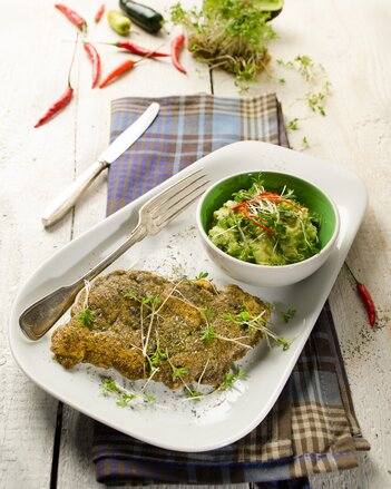 Auf dem Foto sieht man ein Zanderfilet mit Parmesankruste. Daneben steht ein Schälchen mit Dip. Über den ganzen Teller sind Knospen verteilt. | © SONNENTOR