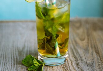 Auf dem Foto sieht man ein Glas mit Zitronen-Ingwer Eistee. Darin sind Minzblätter, Eiswürfel und Limettenscheiben zu sehen. | © SONNENTOR