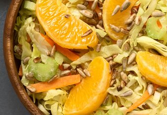 Auf dem Foto ist eine Schüssel mit Salat zu sehen. Darauf sieht man Orangen Spalten. Daneben sind geröstete Sonnenblumenkerne zu sehen. | © SONNENTOR