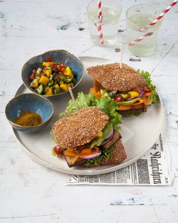 Auf dem Foto sieht man zwei Burger mit Tofu. Daneben sieht man eine Schale mit buntem Gemüse. | © SONNENTOR