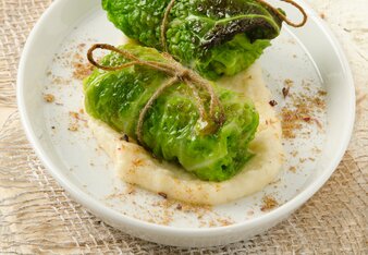 Auf dem Foto sind zwei Stück Emmer-Kohl-Rouladen auf Pastinaken-Apfel Creme zu sehen. Rundherum sind Gewürze verteilt. | © SONNENTOR