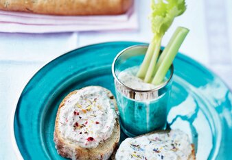 Auf dem Foto ist ein blauer Teller mit zwei Scheiben Brot und Schutzengel Joghurt Aufstrich zu sehen.  Daneben ist der Dip mit Sellerie zu sehen. | © SONNENTOR