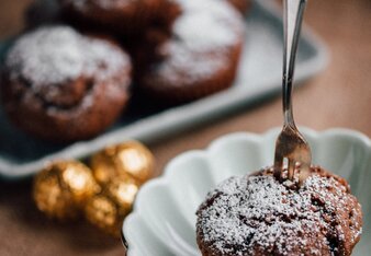 Auf dem Foto sieht man einen Lebkuchen Muffins in dem eine Gabel steckt. Im Hintergrund sieht man noch mehrere Muffins. | © SONNENTOR