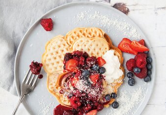 Auf dem Foto ist ein Teller mit Kokoswaffeln zu sehen. Wie sind mit Beeren und Kokosraspeln angerichtet. | © SONNENTOR