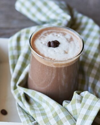 Auf dem Foto sieht man ein Glas mit Kaffee-Schoko-Chili-Smoothie. Das Glas steht auf einem grün-weiß kariertem Tuch. | © SONNENTOR