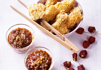 Auf dem Foto ist eine Schüssel mit Fischnuggets zu sehen. Daneben stehen Schälchen mit Tomatenchutney. | © SONNENTOR