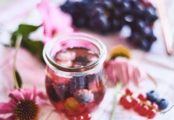 Auf dem Foto ist die Bengelchen Bowle mit Wacholderbeeren zu sehen. Daneben sind Ribiseln, Heidelbeeren und Blüten zu sehen. | © SONNENTOR