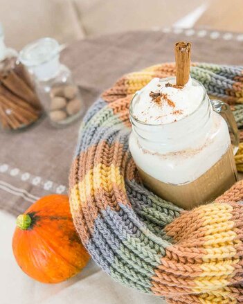 Auf dem Foto ist ein Glas Pumpkin Spice Latte zu sehen. Das Glas ist mit einem bunten Schal eingewickelt. Daneben ist ein Kürbis zu sehen. | © SONNENTOR