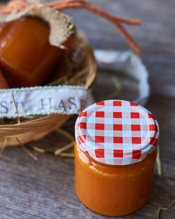 Auf dem Foto sieht man ein Glas mit der orangenen Osterhasen Marmelade. Daneben steht ein Körbchen mit noch einem Glas darin. | © SONNENTOR