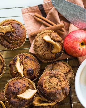 Auf dem Foto sieht man mehrere Muffins. Neben den Muffins sind auch ein Apfel und Zimtstangen zu sehen. | © SONNENTOR