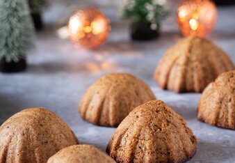 Auf dem Foto sind Mandel-Dattelplätzchen zu sehen. Im Hintergrund sieht man eine Lichterkette und Miniatur Christbäume. | © SONNENTOR