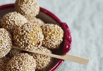 Foto von einer bunten Schüssel mit Couscous Bällchen darin. Ein Bällchen ist auf einem Holzstäbchen aufgespießt. | © SONNENTOR