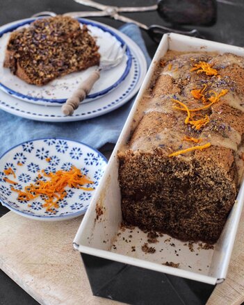 Auf dem Foto ist eine Backform mit Mohn-Karotten Kuchen zu sehen. Daneben steht ein Teller auf dem bereits ein Stück Kuchen liegt. | © SONNENTOR