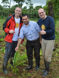 Photo showing two Sonnentor employees and a farmer standing in a field. | © SONNENTOR