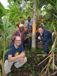 In the photo you can see two Sonnentor employees and farmers standing around a cinnamon tree. | © SONNENTOR