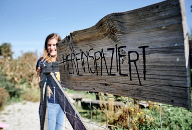 Auf dem Foto ist ein Tor mit einem Schild zu sehen, auf dem Schild steht hereinspaziert. | © SONNENTOR