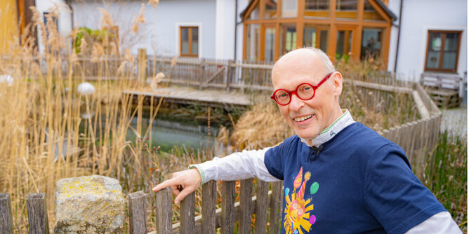 Am Foto steht Hannes am Gartenzaun des Teiches im Innenhof des Bauernhofs.  | © SONNENTOR