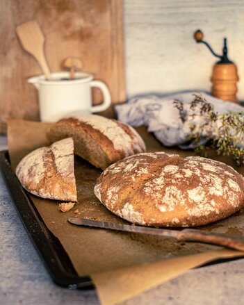 Auf dem Foto ist ein Laib Dinkelbrot zu sehen. Dahinter liegt noch ein Laib das in der Mitte durchgeschnitten ist. | © SONNENTOR