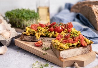 Auf dem Foto sind zwei Scheiben Sauerteigbrot zu sehen. Darauf befindet sich Kurkuma Eierspeise und Tomaten. | © SONNENTOR