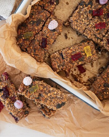 Auf dem Foto sieht man ein Blech mit Flocken-Beeren Riegel. Diese sind mit Joghurt-Fruchtgummis dekoriert. | © SONNENTOR