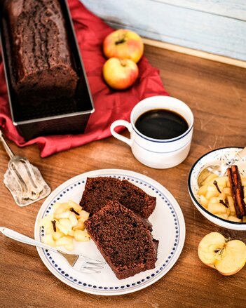 Auf dem Foto sind zwei Stück Schokoladen-Mandelkuchen zu sehen. Daneben sieht man Apfelkompott mit Nelken. | © SONNENTOR