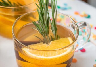  New Year's tea is served in a glass cup decorated with rosemary sprigs and half lemon slices. | © SONNENTOR