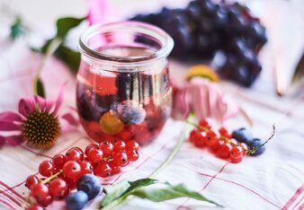 Auf dem Foto sieht man eine Cocktail Bowle. Daneben sind Heidelbeeren und Ribisel zu sehen. | © SONNENTOR