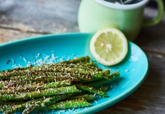 Auf dem Foto ist gegrillter grüner Spargel zu sehen. Er ist mit Parmesan bestreut. | © SONNENTOR