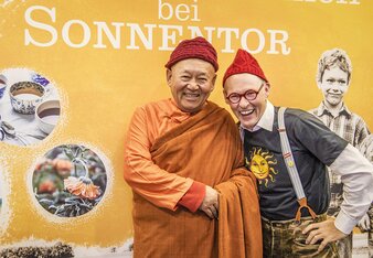 Auf dem Foto sieht man Kyabgögn Chetsang mit Johannes Gutmann vor einer Sonnentor Tafel. | © SONNENTOR