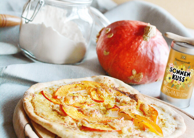 Auf dem Foto sieht man eine Sonnenkuss Focaccia mit Kürbis. Dahinter sieht man eine Dose mit Sonnenkuss Gewürzblüten. | © SONNENTOR